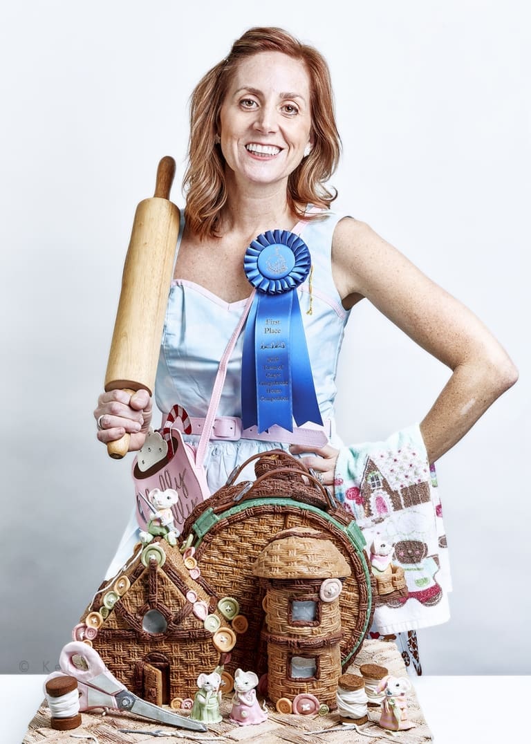 Woman with gingerbread house and rolling pin.