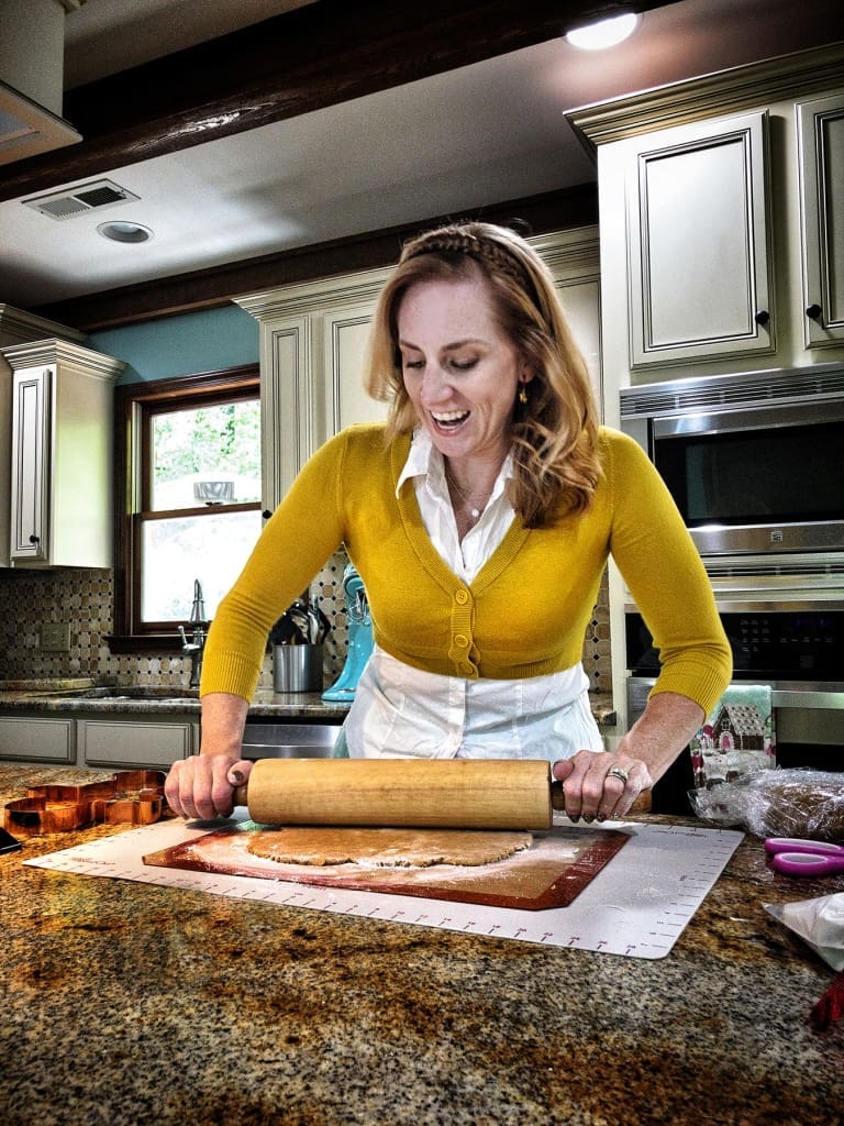 Woman rolling dough on kitchen counter.