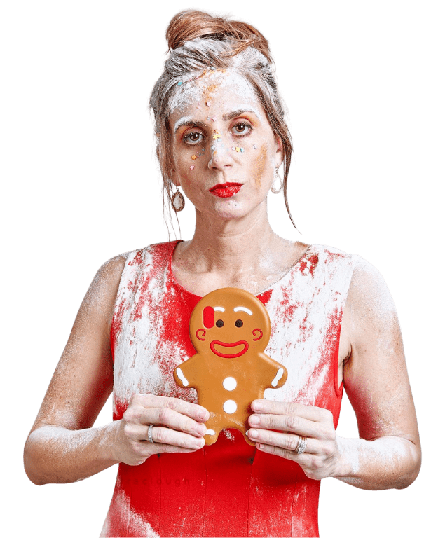 Woman holding gingerbread man, covered in flour.